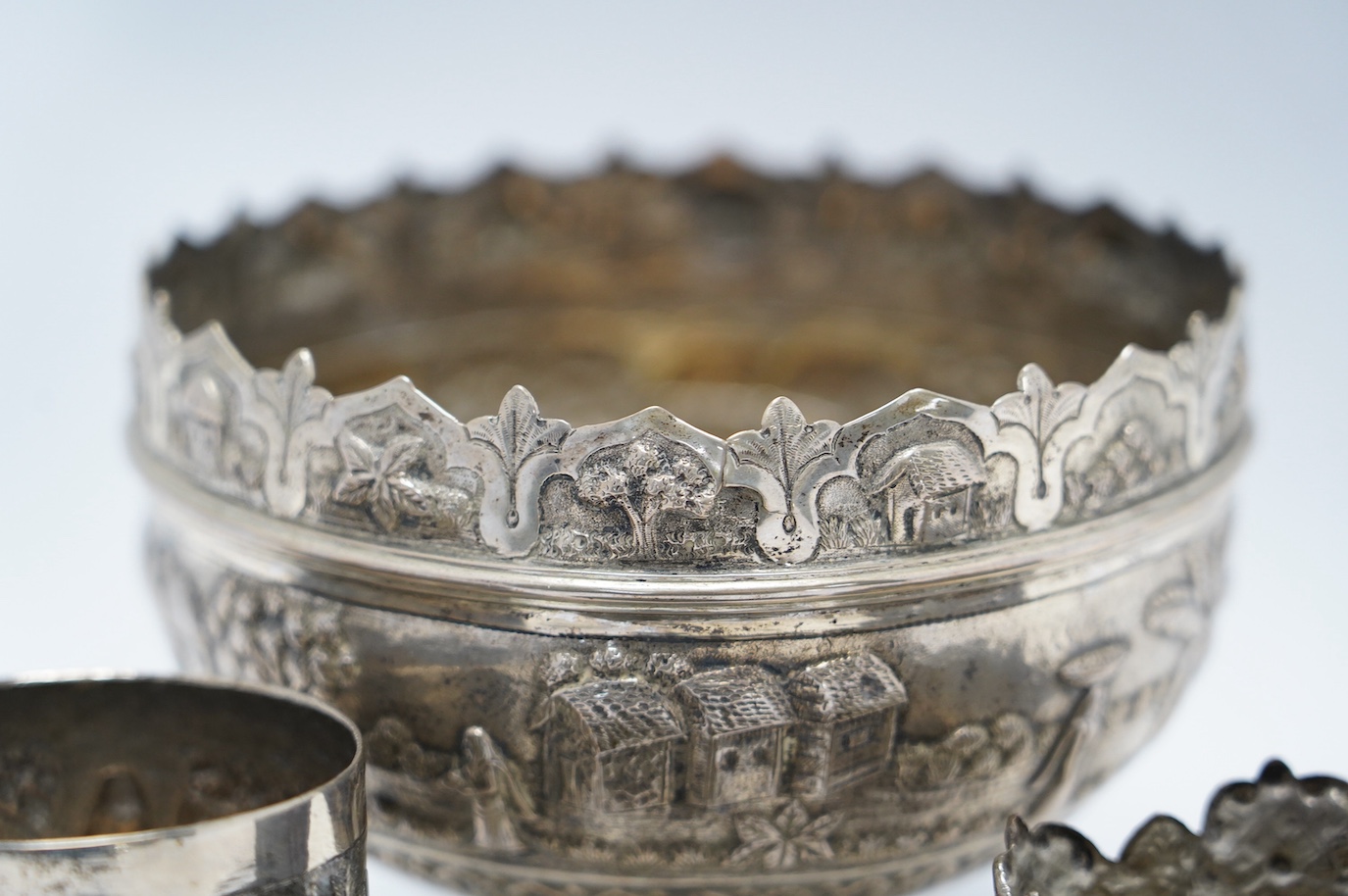 An Indian repousse white metal pedestal bowl, diameter 15.5cm (a.f.), a similar mug, small vase, condiment and small beaker. Condition - poor to fair